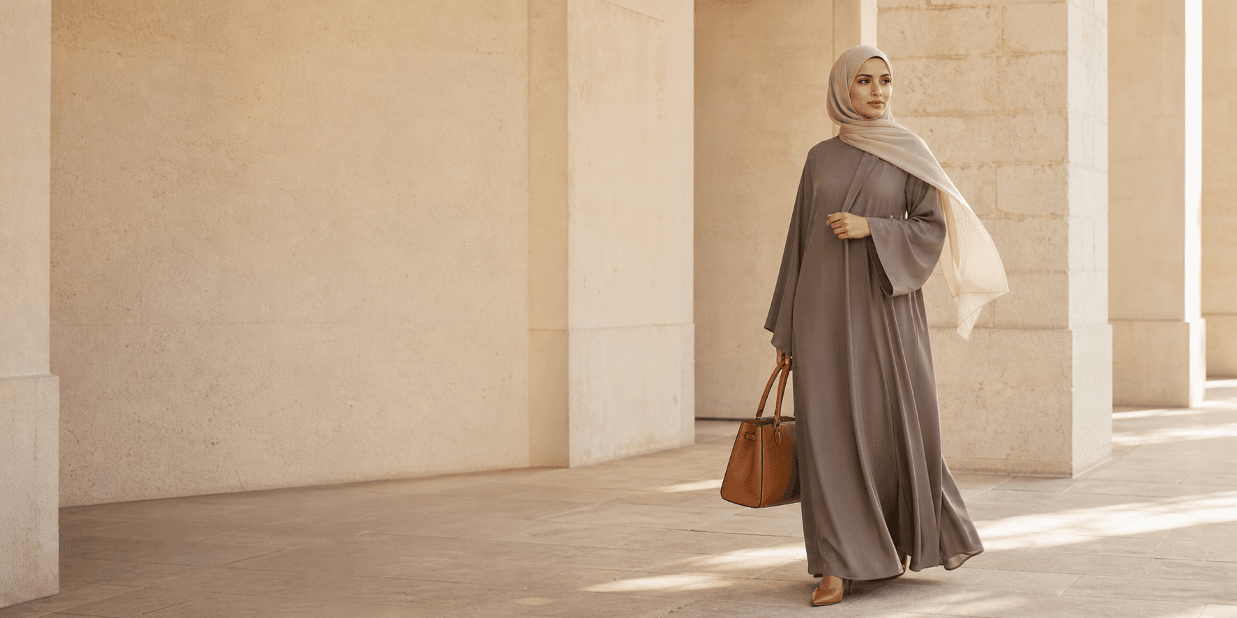 Femme portant un voile taupe et un sac camel dans une architecture lumineuse